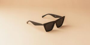 Modern black sunglasses with a sleek design on a neutral background, perfect for lifestyle themes.